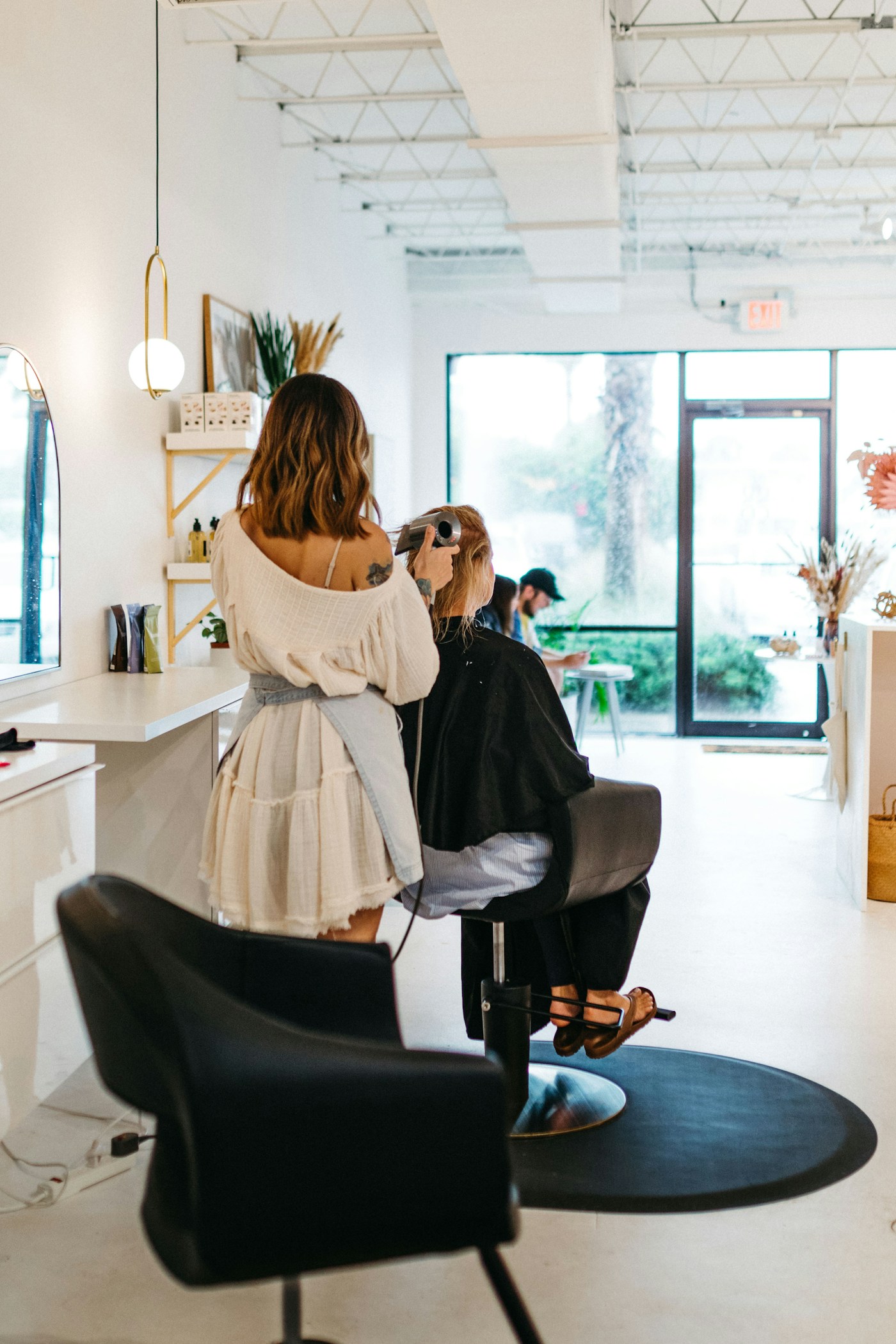 A stylist giving a client her full attention in a sunlit salon